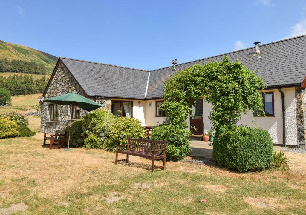 a house with two benches in front of it at Maes Mihangel in Llanfihangel-y-Pennant