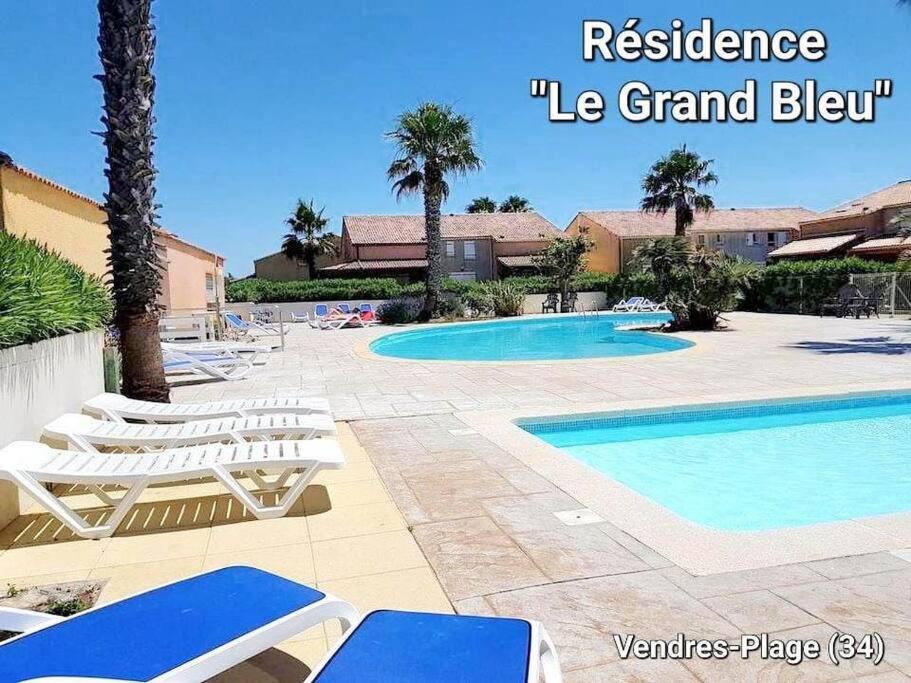 une piscine avec des chaises longues et une piscine dans l'établissement Gîte VILLA 34 Résidence Le Grand Bleu, à Vendres