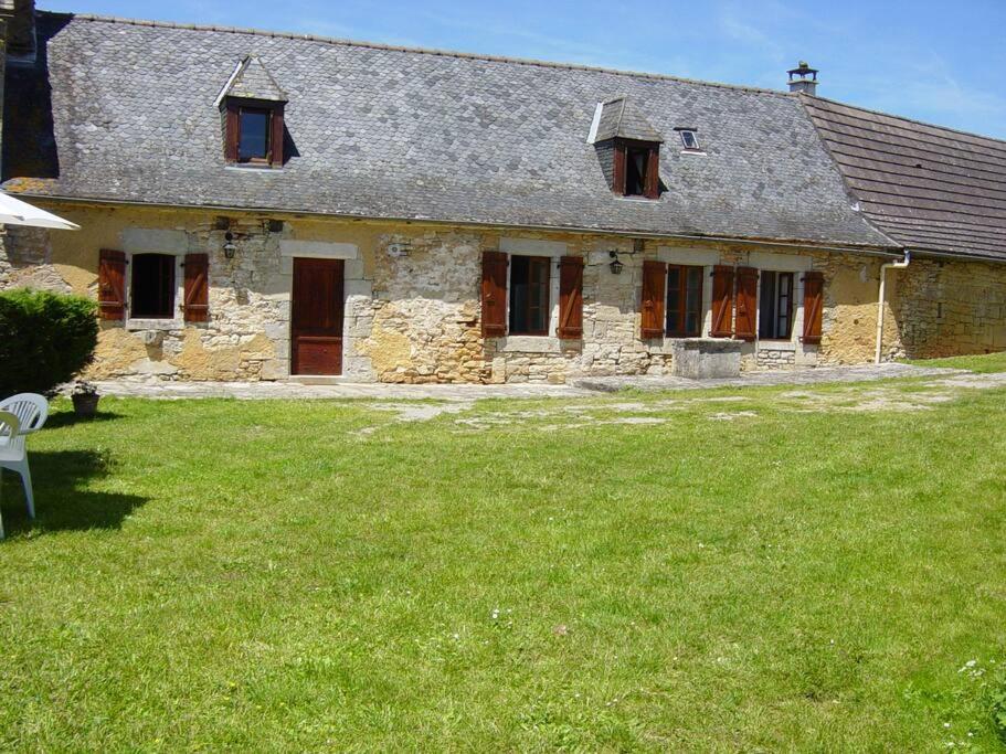 an old stone house with a grass yard at Charmante maison de campagne in Chasteaux