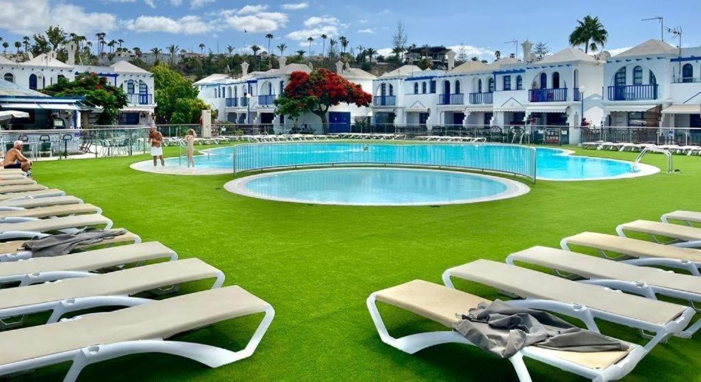 a swimming pool with lounge chairs on a green lawn at Maspalomas Casa Oceano in Maspalomas