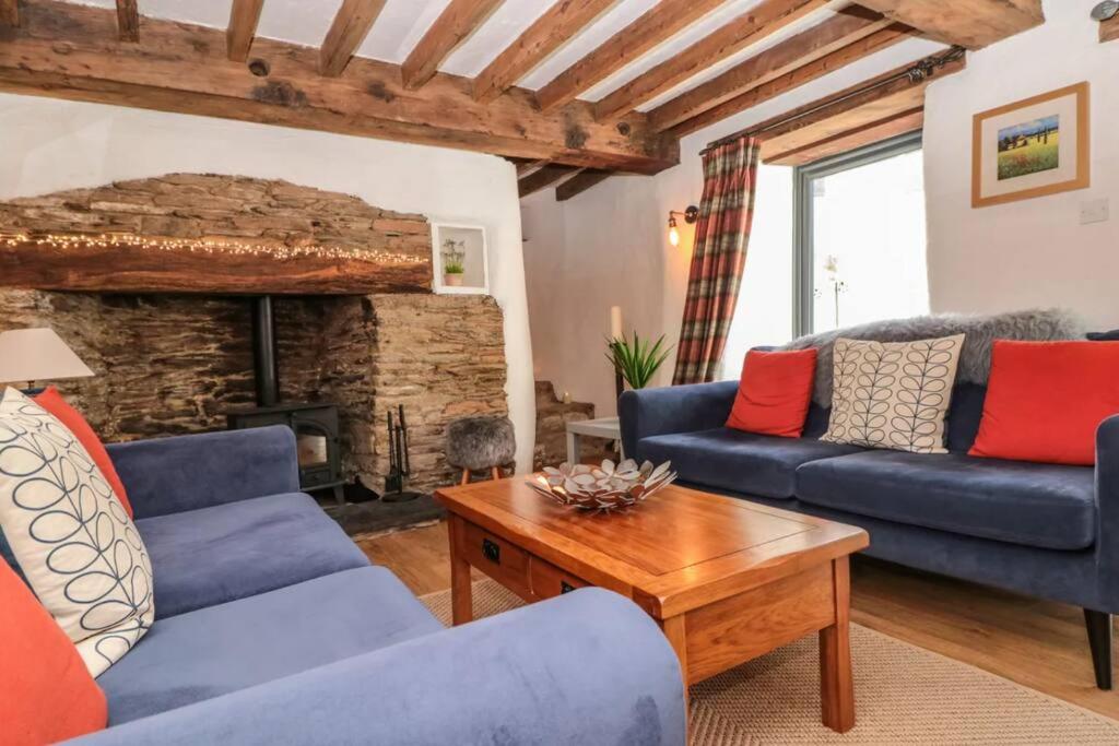 een woonkamer met twee blauwe banken en een open haard bij Court Cottage - cosy traditional cottage near lovely beaches in Kingsbridge