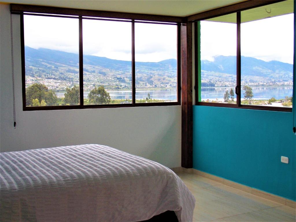 um quarto com grandes janelas com vista para a cidade em HOSTAL Casa Verde em Otavalo