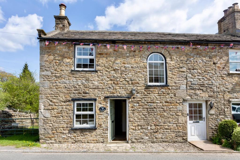 an old stone house with garlands on it at Character Cottage In West Burton, Wensleydale in West Burton