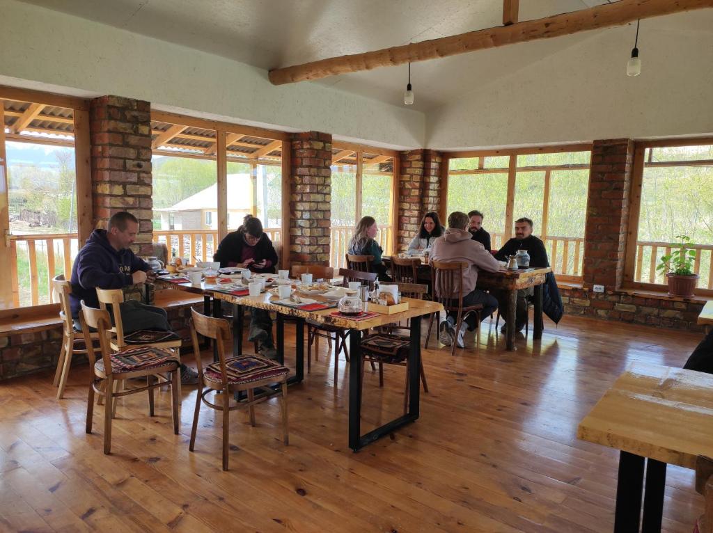 eine Gruppe von Personen, die in einem Restaurant an Tischen sitzen in der Unterkunft Eco Village Lodge in Dzhetyoguz