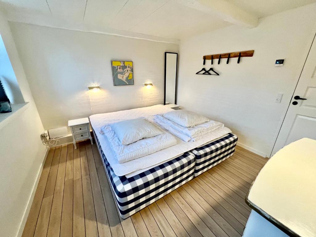 a bedroom with a large bed with white sheets at Lækkert byhus i hjertet af Marstal in Marstal
