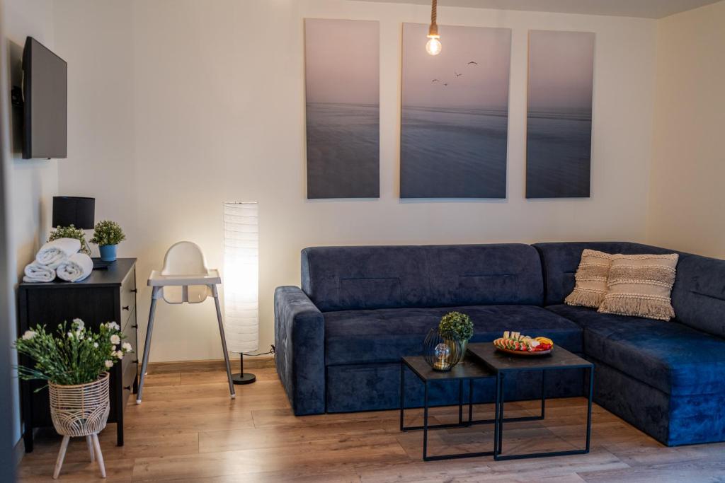 a living room with a blue couch and a table at Karwia Marina Apartamenty in Karwia