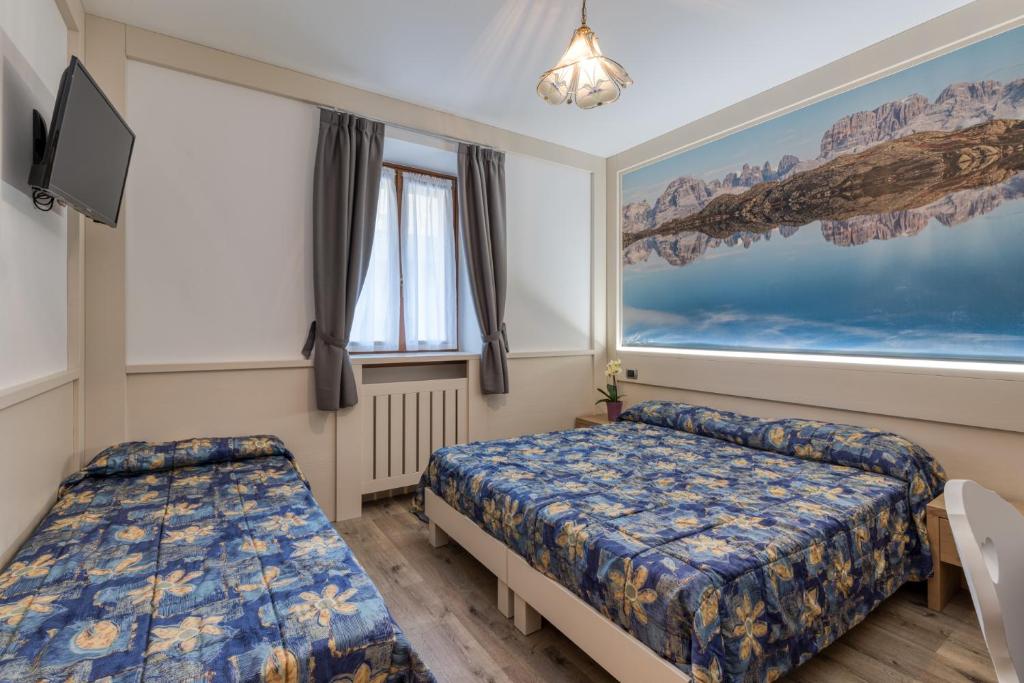 a bedroom with two beds and a tv at Hotel Al Sole in Saone