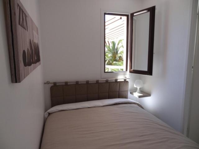 een slaapkamer met een bed met een raam erin bij Appartement Saint Cyprien vue mer et piscine in Saint-Cyprien
