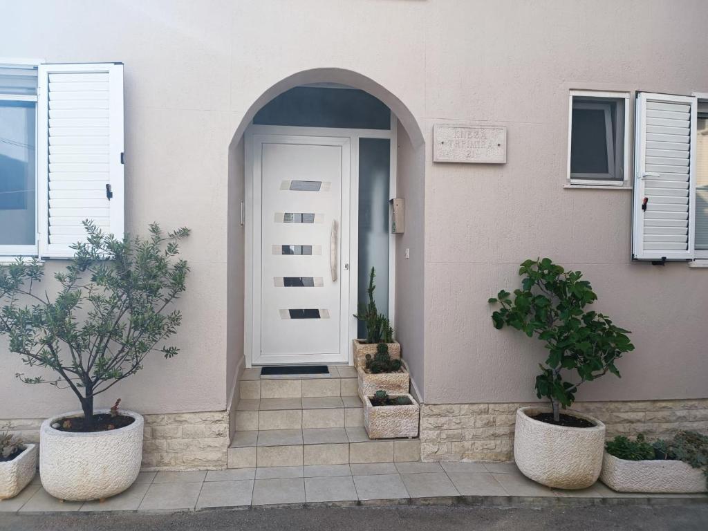 a front door of a house with two potted trees at Apartments Vrime in Biograd na Moru