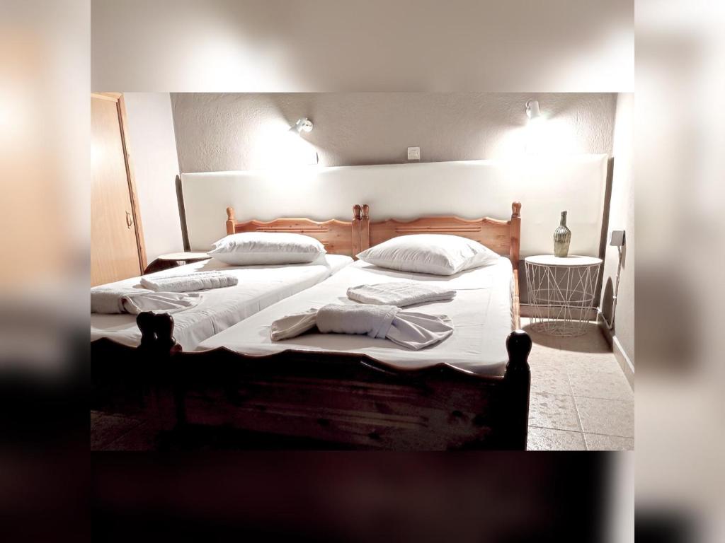 una camera con 2 letti con lenzuola e cuscini bianchi di Le stanze del tramonto di Eleni a Lisso (Lipsoi)