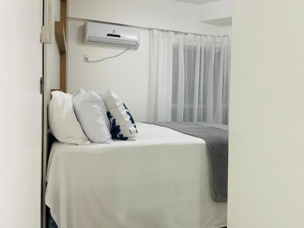 Un dormitorio con una cama con sábanas y almohadas blancas. en MAR doce LAR, en Maceió