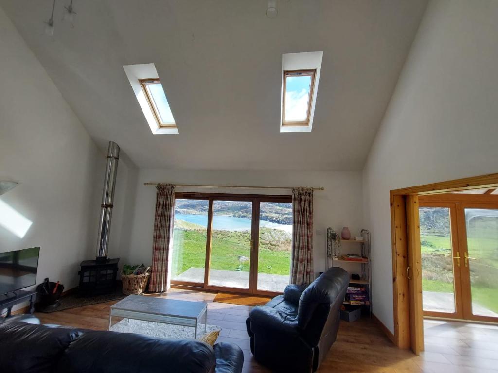 a living room with a couch and chairs and windows at Ocean Surf in Clashnessie