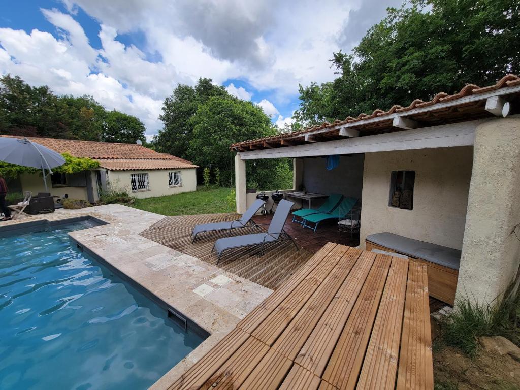 un patio trasero con terraza de madera y piscina en Villa climatisée piscine, en Cadenet