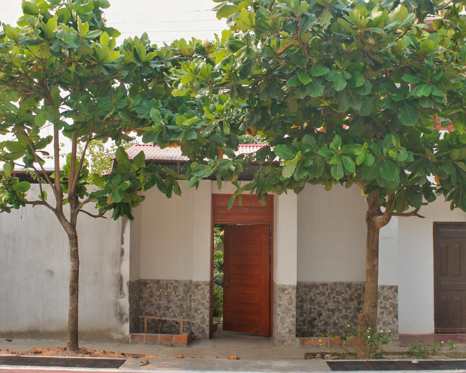 een gebouw met een houten deur en twee bomen bij Casa Albina in Yurimaguas