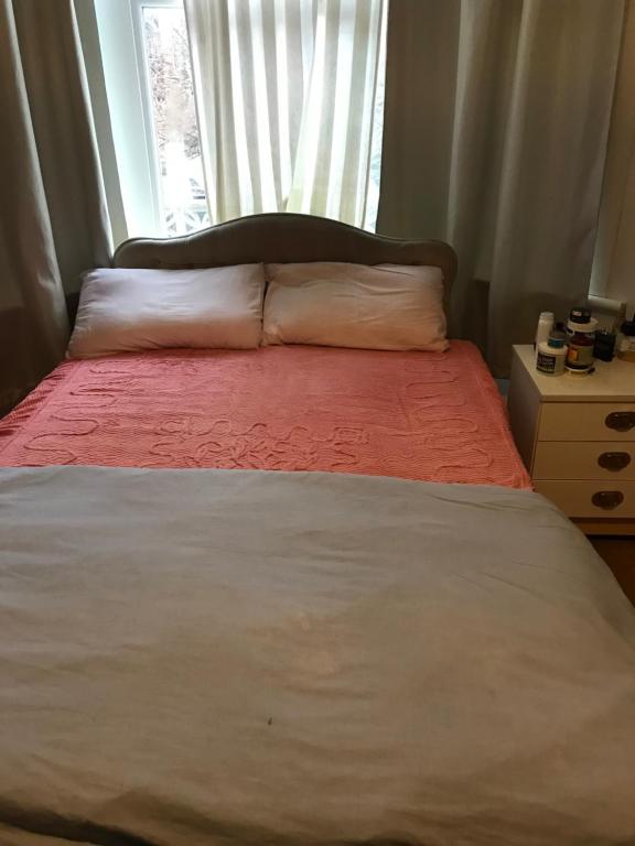 a bed with a red blanket and a window at Devons Unique Short Stay in London