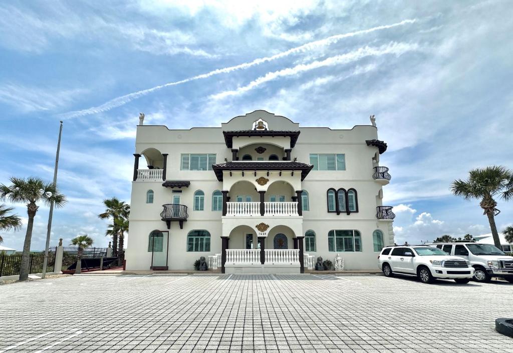 un gran edificio blanco con coches aparcados en un aparcamiento en Bliss By The Sea en Saint Augustine