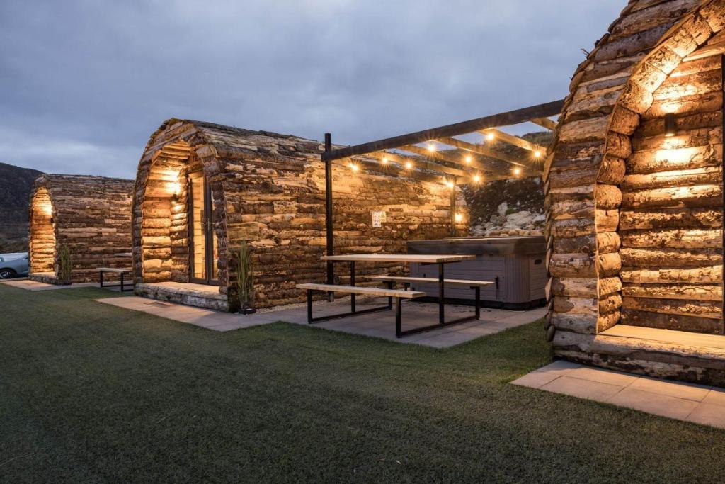 a stone building with a picnic table with lights on it at Greenview Glamping Pods in Bannvale