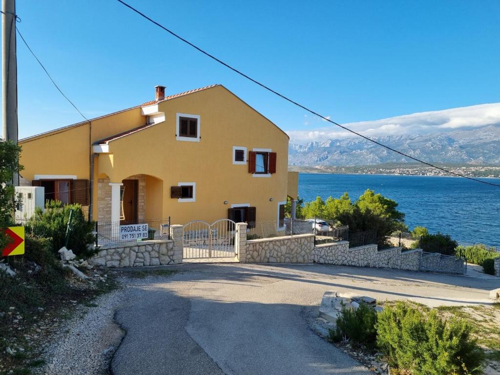 una casa amarilla con el océano en el fondo en Apartments Mikecin en Novigrad Dalmatia