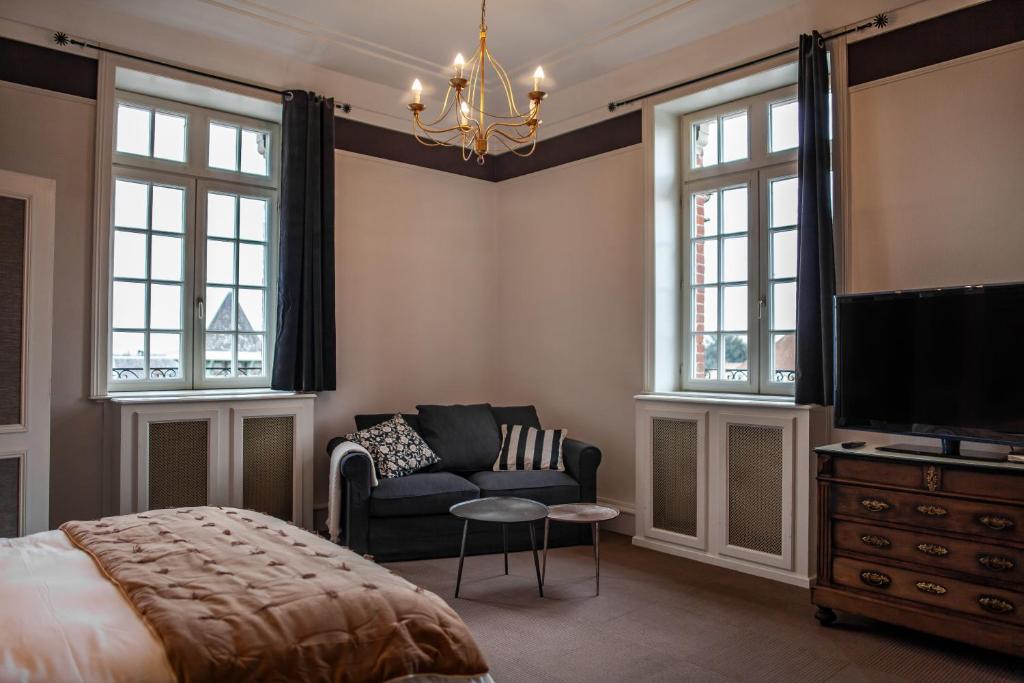 a bedroom with a bed and a couch and a tv at MAISON RENARD in Béthune