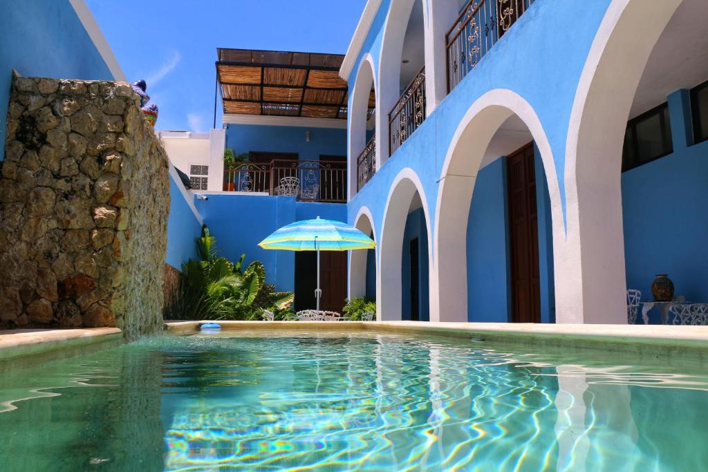 - une piscine en face d'un bâtiment avec un parasol dans l'établissement Boutique Casa Azuli Santiago, à Mérida