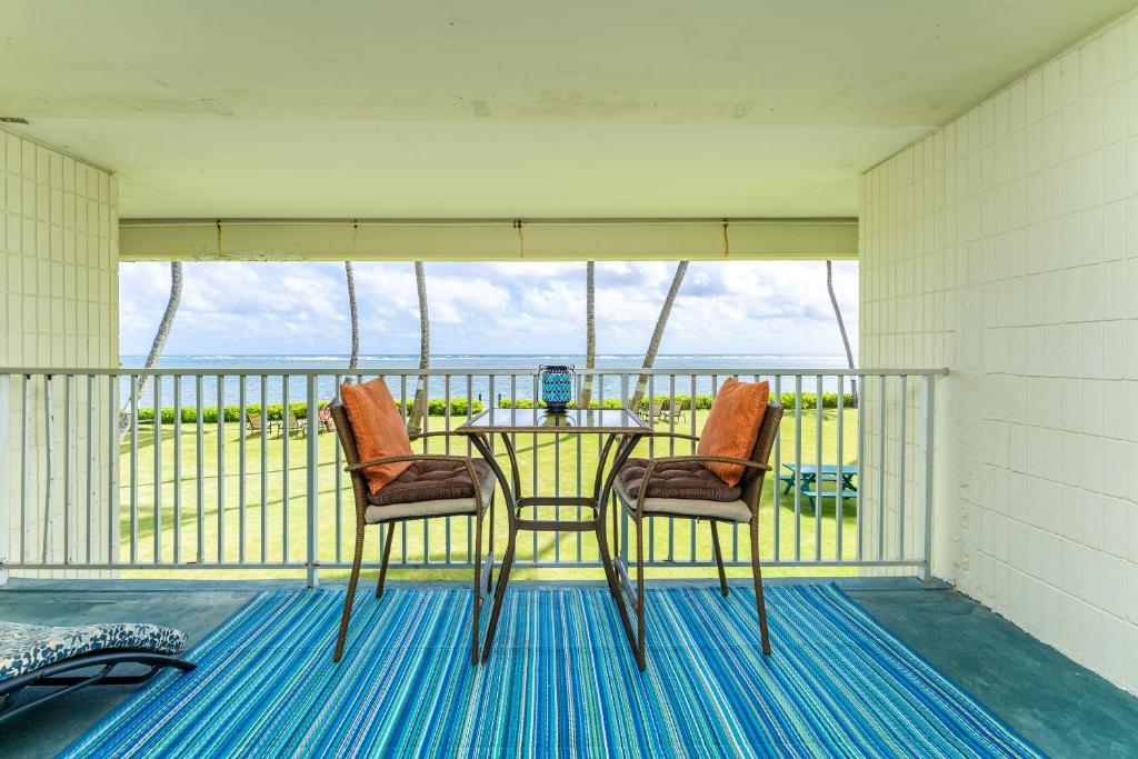 parawan na werandzie ze stołem i dwoma krzesłami w obiekcie The Location! Aloha Soul Beachfront w mieście Laie