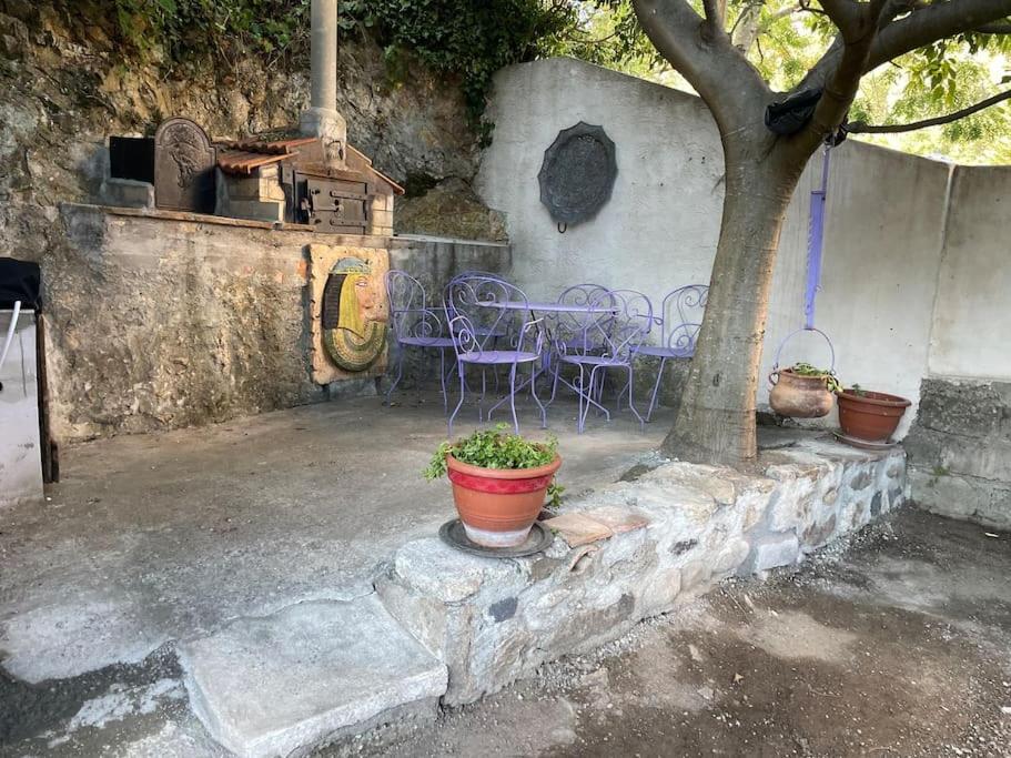 a patio with a table and chairs and a tree at Maison de village le BACCI in Vals-les-Bains
