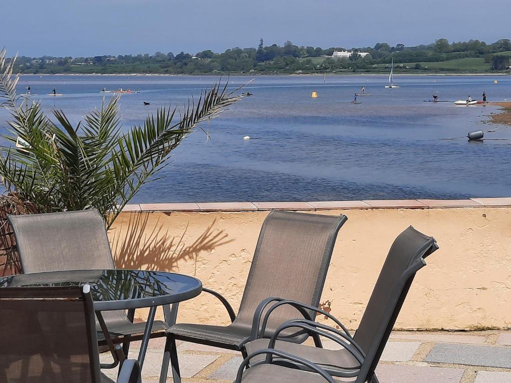 two chairs and a table with a view of a body of water at Driftwood in Exmouth