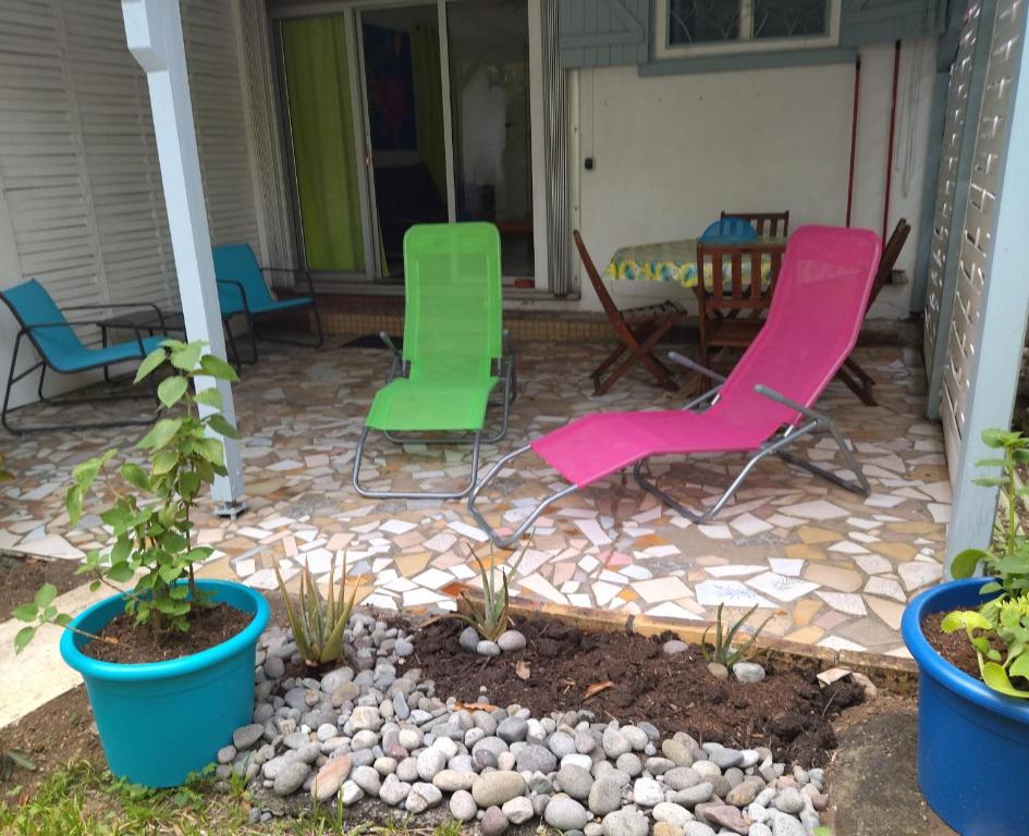 eine Terrasse mit 2 Gartenstühlen und einem Tisch in der Unterkunft Chez Caroline in Basse-Terre