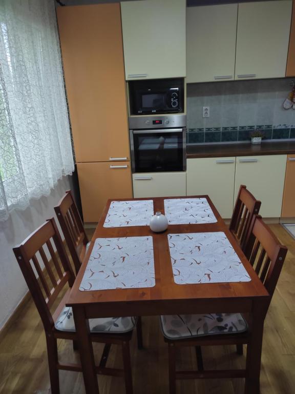 eine Küche mit einem Holztisch mit Stühlen und einem Backofen in der Unterkunft Apartman Emilija in Bačka Palanka
