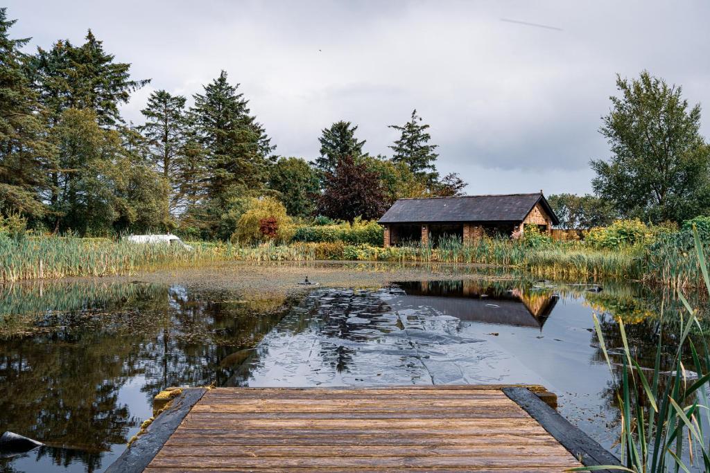 a wooden dock in front of a lake with a building at Luxury Retreat -Perfect To Explore The North Coast in Macosquin