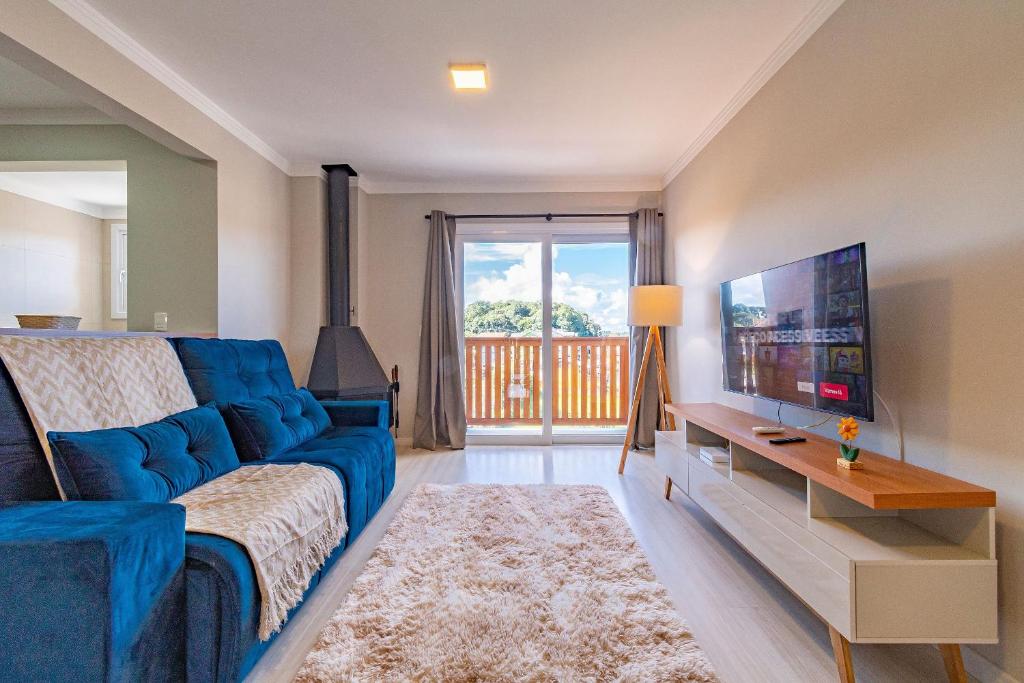 ein Wohnzimmer mit einem blauen Sofa und einem Fernseher in der Unterkunft Excelente ap em Canela - @stayhousetemporada in Canela