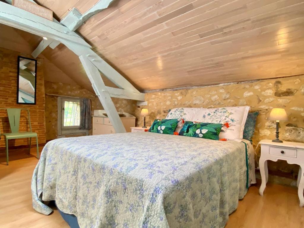 a bedroom with a bed and a stone wall at Le chant des oiseaux in Tourliac
