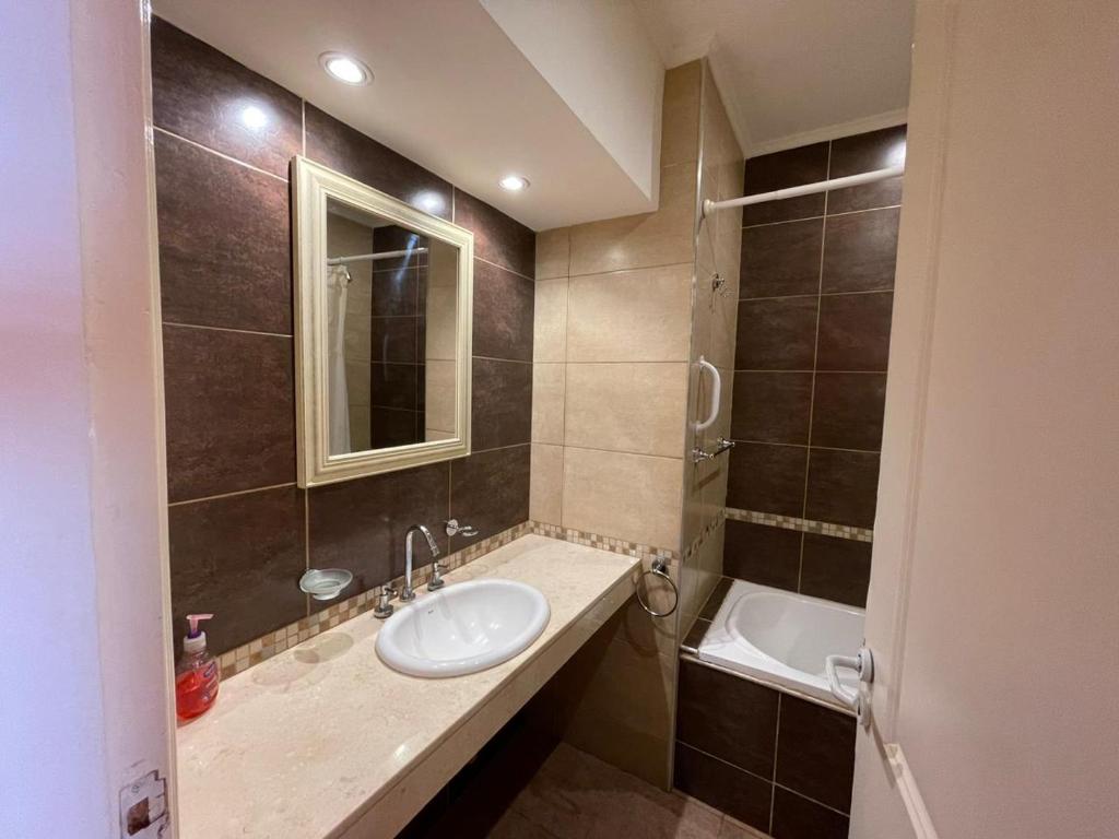 ein Badezimmer mit einem Waschbecken, einem Spiegel und einer Badewanne in der Unterkunft Tu casa en parque in Necochea