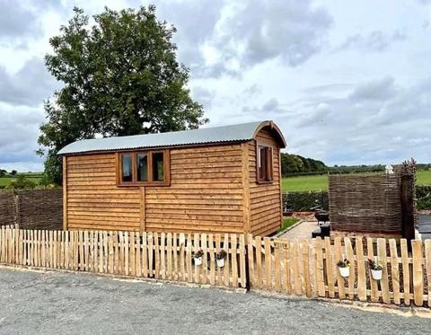 a small wooden house behind a wooden fence at Spinney View Huts 