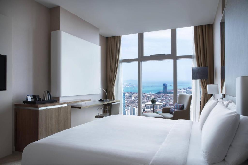 イスタンブールにあるイスタンブール マリオット ホテル シシュリのベッドと大きな窓が備わるホテルルームです。
