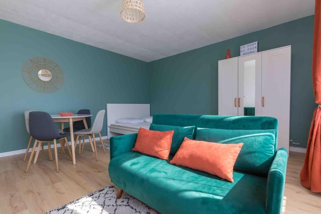 a living room with a green couch and a table at Le Cosy du Faux Bourg in Châlons-sur-Marne