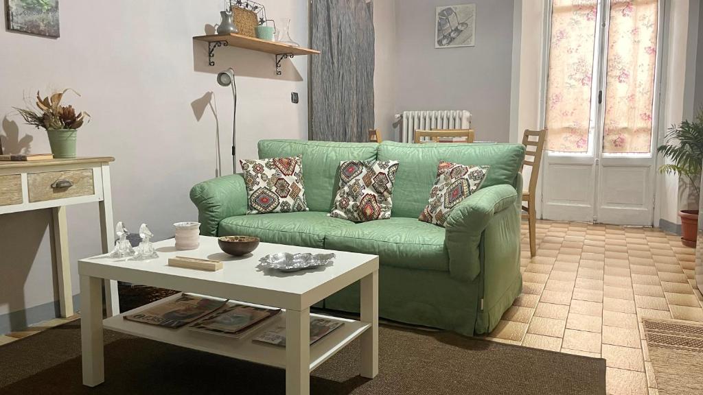 uma sala de estar com um sofá verde e uma mesa em Historical Duomo Apartment Alba em Alba