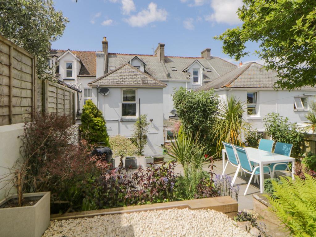 un jardín con mesa y sillas frente a una casa en Midhurst en Brixham