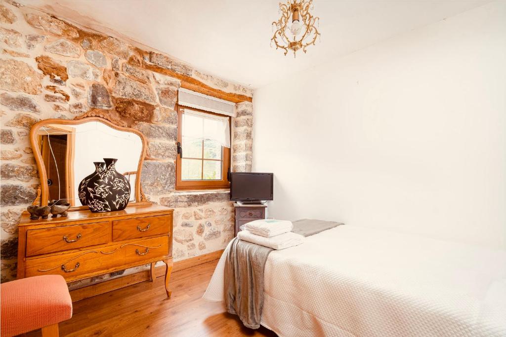 a bedroom with a stone wall with a dresser and a mirror at Villabu Babia in San Emiliano