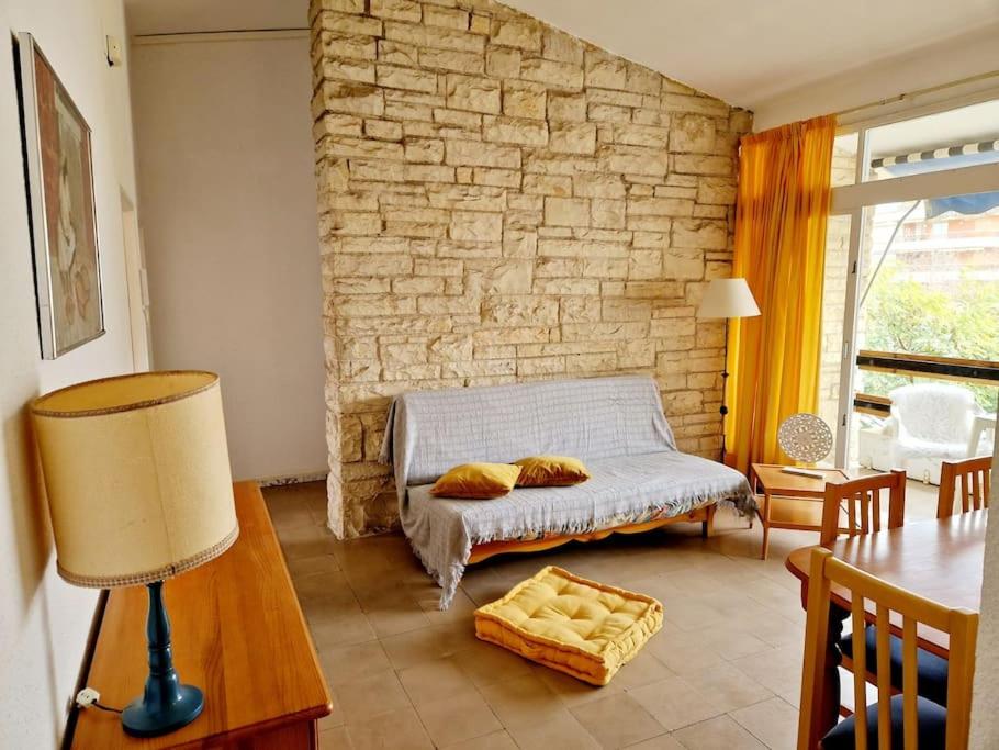 sala de estar con cama y pared de piedra en Apartamento a un paso de playa, en Salou