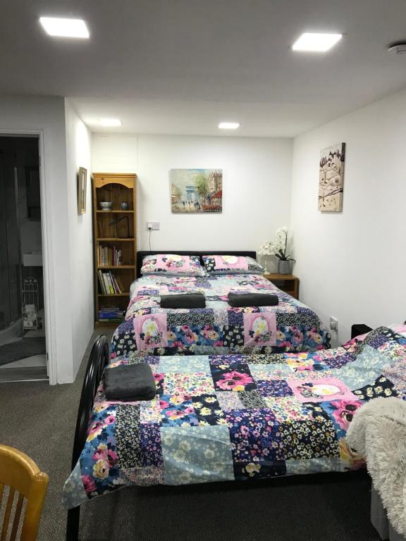 a room with three beds with quilts on them at Annexe in lymington with private use of hot tub in Everton