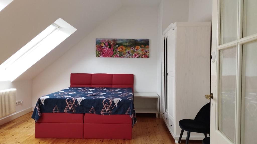 ein Schlafzimmer mit einem roten Bett und einem Gemälde an der Wand in der Unterkunft MannheimMitte Zimmer3 Denkmalschutz Stadthaus - 2 Personen in Mannheim