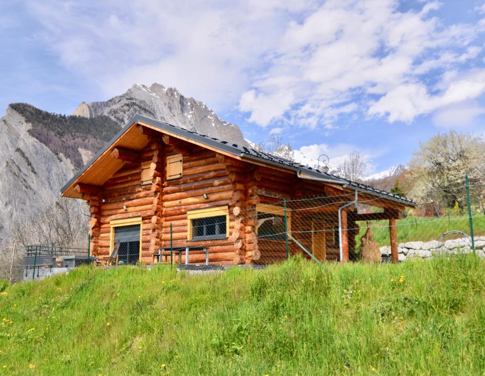 a log cabin on a hill with a mountain in the background at L'Etoile du Berger in Saint-Martin-de-la-Porte