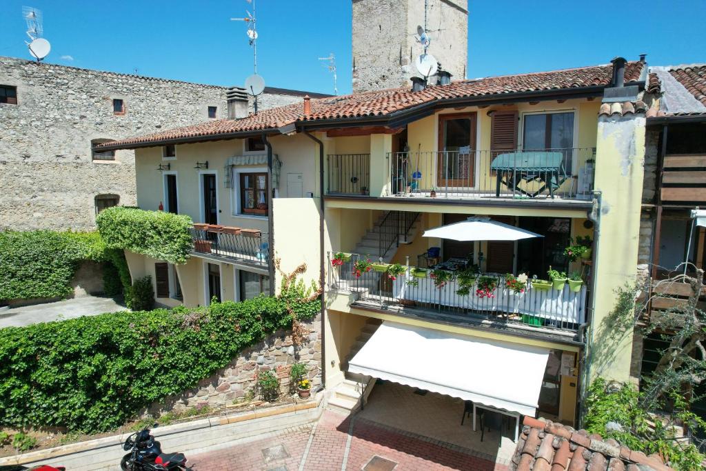 un edificio de apartamentos con balcón con sombrilla en Manerba CENTRO GardaSee e parcheggio, en Manerba del Garda