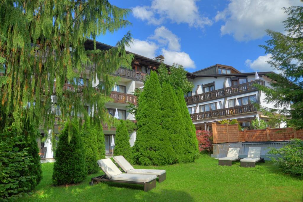 ein Gebäude mit einem Garten mit Stühlen und Bäumen in der Unterkunft Kurhotel Eichinger in Bad Wörishofen