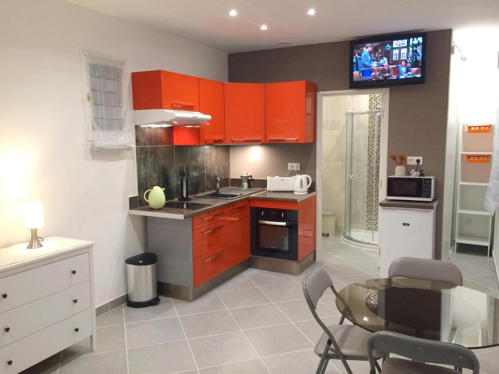 Il comprend une cuisine avec des placards rouges, une table et une télévision. dans l'établissement Telerues, à Nice