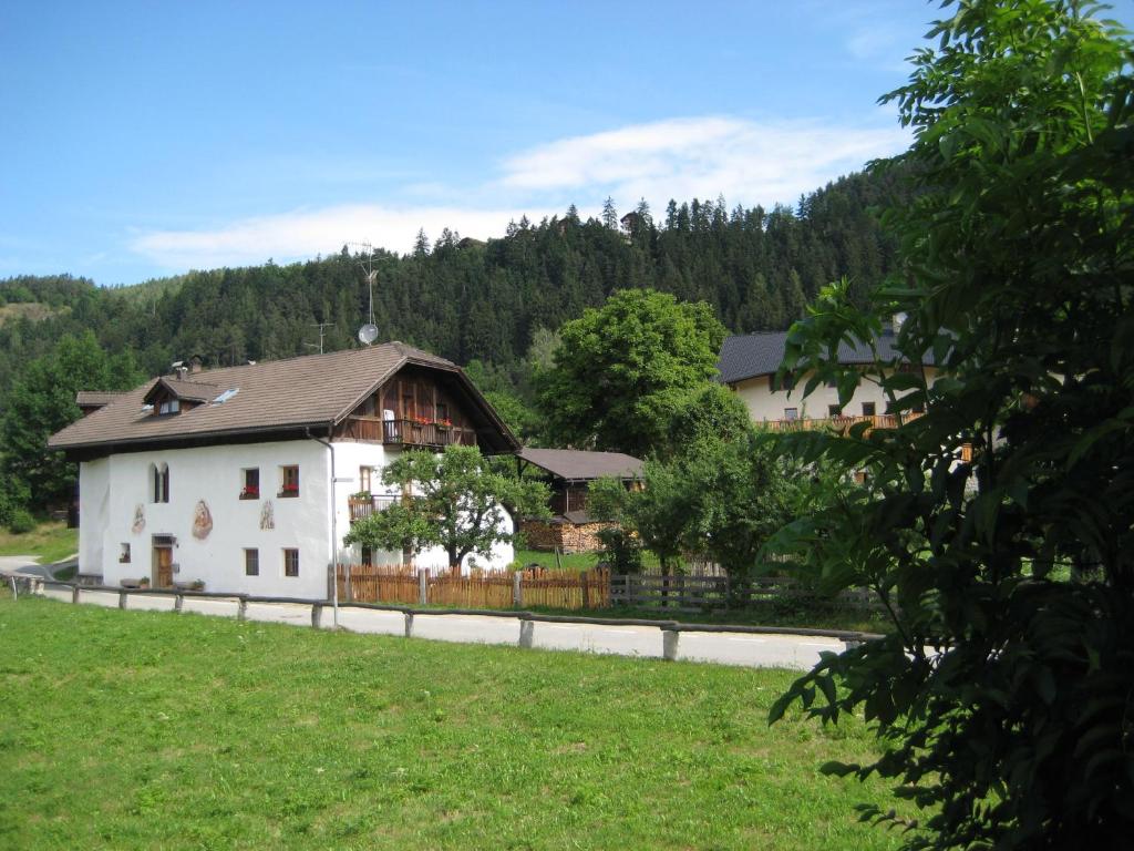 una casa blanca con una valla en un campo en Krüglwirt, en San Lorenzo di Sebato