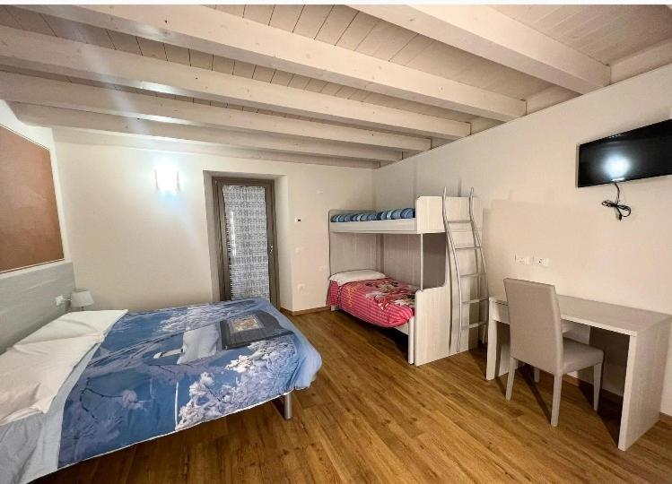 Gratacasolo的住宿－Osteria Carli B&B，一间卧室配有一张床、一张桌子、一张床和一张双层床。