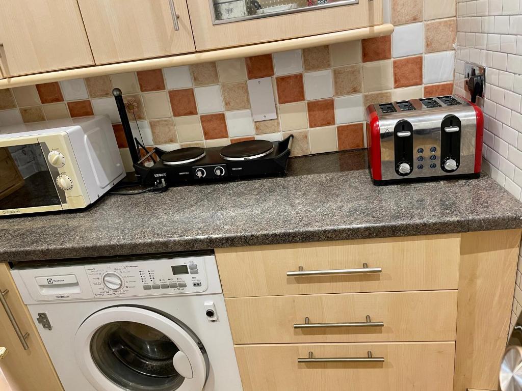 a kitchen with a microwave and a washing machine at Boscote in Stratford-upon-Avon