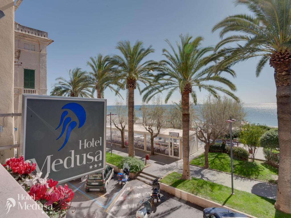 a sign for a hotel in a resort with palm trees at Hotel Medusa in Finale Ligure